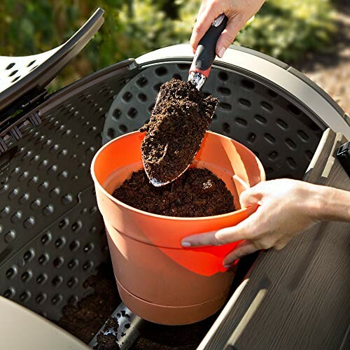 Person scooping compost into an orange bucket from a compost bin.