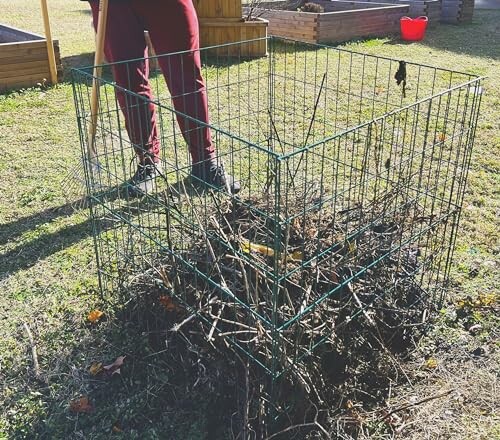 Person standing next to a garden compost bin filled with sticks.