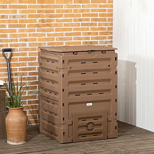 Brown outdoor compost bin on a wooden deck near a brick wall.