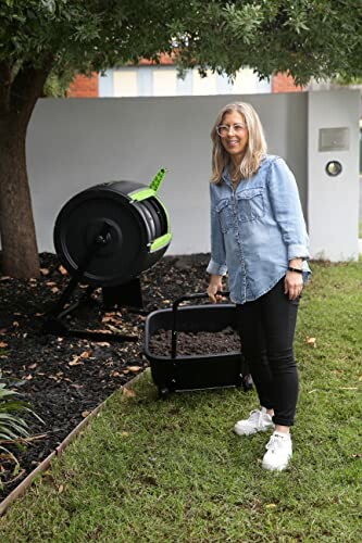 Woman standing next to a compost bin in a garden.